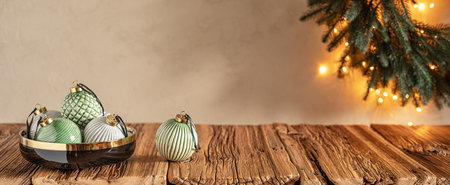 Pastel colored cozy Christmas background with baubles in black bowl on wooden table and wreath on wallの写真素材