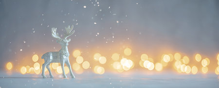 Shallow depth of field image of a Christmas deer figurine in a snowy landscape with bokeh lightsの写真素材