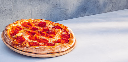 Pepperoni pizza on kitchen table in sunlightの写真素材
