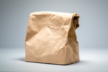 Brown paper bag with unknown contents on a neutral background.の写真素材