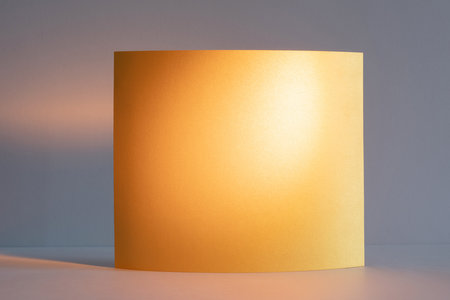 Soft sunlight casts a warm glow on a curved piece of golden yellow orange paper. Texture background.の写真素材