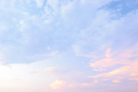 Soft pastel clouds fill the sky at sunset over a serene horizon during a tranquil evening in nature.の写真素材