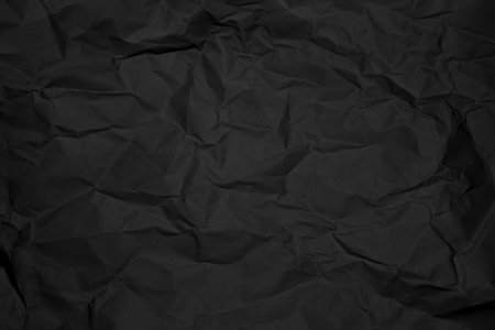 Crumpled black paper texture offering depth and visual interest for background.の写真素材