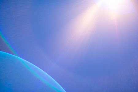 Bright lens flare enhances the vibrant blue sky with hints of celestial curvature.の写真素材