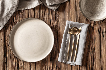 Elegant dining setup with rustic wooden table and chic tableware arranged for mealtime enjoyment.の写真素材