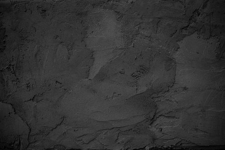Close-up view of a dark gray, rough-textured concrete surface, providing a simple, moody backdrop.の写真素材