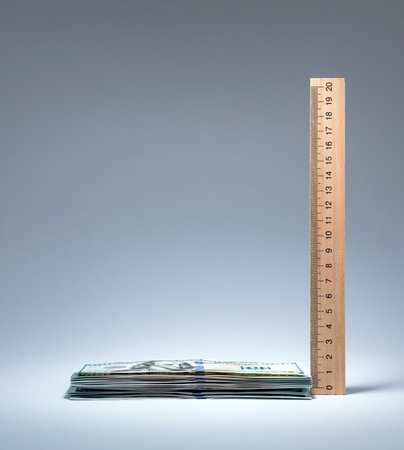 Wooden ruler next to pile of cash. Earnings profit savings expenses taxes. Finances measurement and accounting concepts.の写真素材
