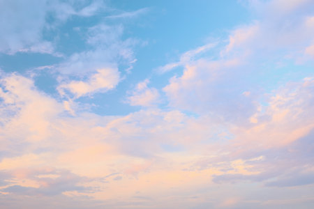 Soft pastel colors fill the sky as clouds drift gently during sunset, painting a tranquil scene that evokes peace and calmness in the early evening light.の写真素材