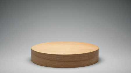 A round wooden display pedestal sits center stage, featuring a smooth surface and natural finish. The gradient gray background provides a neutral contrast, suitable for product showcasing.の写真素材