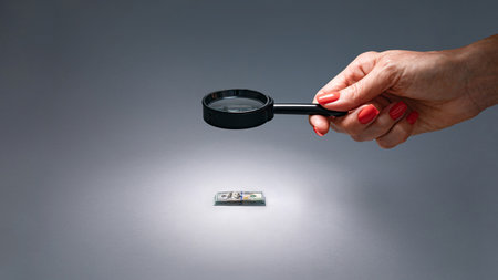 Visual of financial audit using magnifying glass to check expenses and income.の写真素材