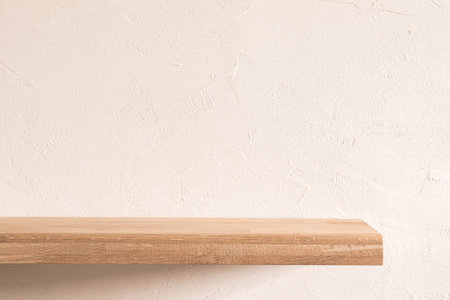 Natural oak wood shelf against textured warm white wall in minimalist interior space. Background.の写真素材
