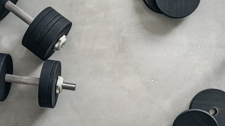 Heavy dumbbells arranged on a gray workout surface for strength training and fitness activities. Copy space texture background.の写真素材
