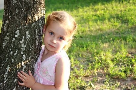 Beautiful girl at the tree trunk in summerの写真素材