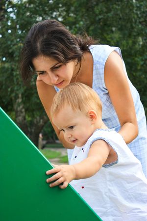Little baby girl with mother in playground outdoorの写真素材