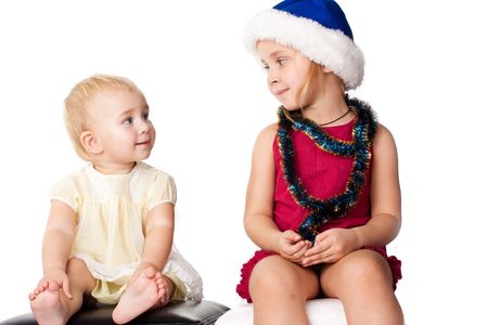 Baby looking at the sibiling sister in Santa's blue hat and tinselの写真素材