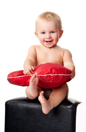 Beautiful baby sitting with heart shaped red pillowの写真素材