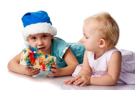Girl in Santa'sblue hat giving out a present to a baby isolated on whiteの写真素材