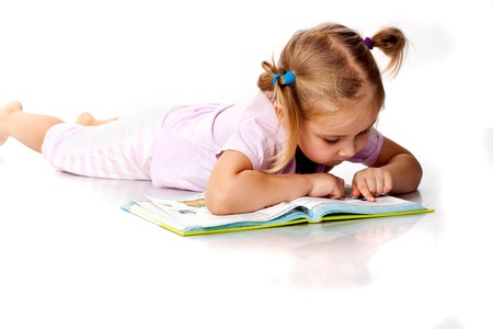 Beautiful girl lying reading a bookの写真素材
