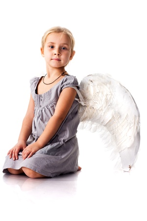Beautiful girl with angel wings sitting isolated on whiteの写真素材