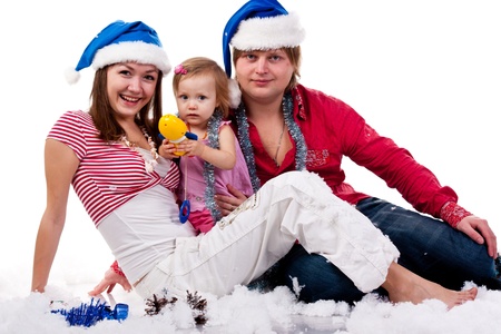Family in Santa's hat sitting in artificial snow isolated on whiteの写真素材