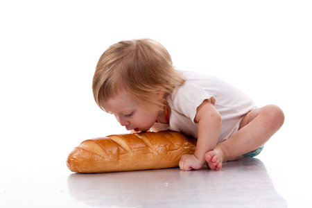 Babytrying to bite a loaf of bread  isolated on white
