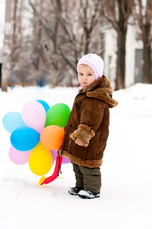 Beautiful girl playing with baloons outdoor in winterの写真素材