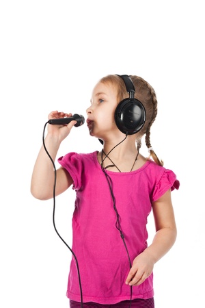 Beautiful girl in headphones with microphone singing isolated on whiteの写真素材