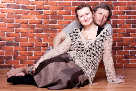 Happy seniors couple in love against brick wallの写真素材