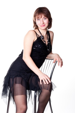 Beautiful young woman sitting on a bar chair isolated on whiteの写真素材