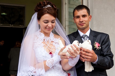 Happy groom and bride holding wedding pigeons in handsの写真素材