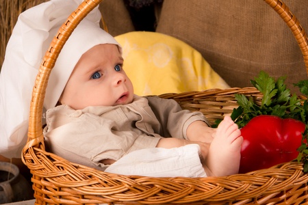 little boy in the cook costume in a basket at the kitchen の写真素材
