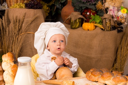 little boy in the cook costume at the kitchen の写真素材