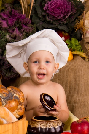 little boy in the cook costume at the kitchen の写真素材