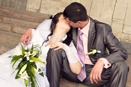 Happy bride and groom kissing on stairs outdoorの写真素材