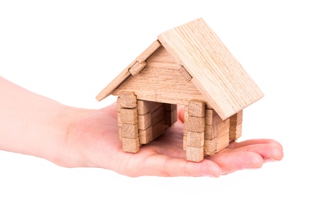 Wooden model house in a hand isolated on whiteの写真素材
