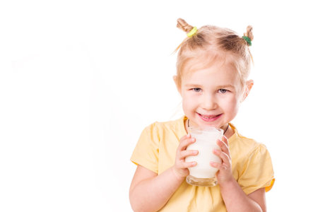 Beautiful little girl holding a cup of milk isolated on whiteの写真素材