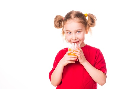 Cute little girl holding glass with juice smiling isolated on whiteの写真素材