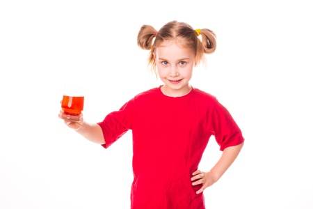 Cute little girl holding glass with juice smiling isolated on whiteの写真素材