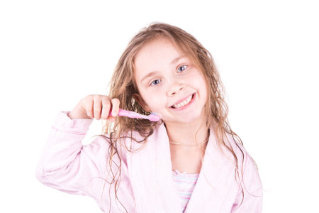 Beautiful happy smiling little girl brushing her teeth after bath, shower isolated on white
