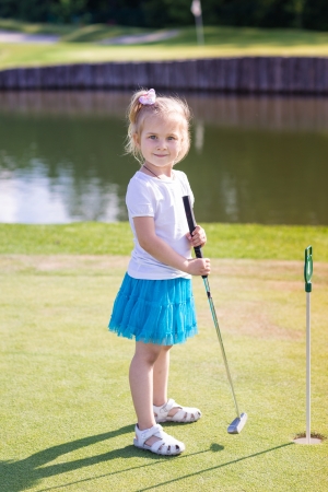 Cute little girl playing golf on a field outdoorの写真素材