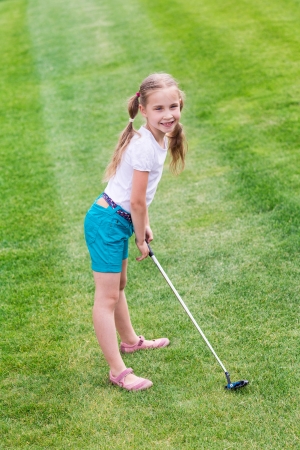 Cute little girl playing golf on a field outdoorの写真素材
