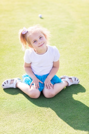 Cute little girl playing golf on a field outdoorの写真素材