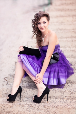 Beautiful young girl in a beautiful dress sitting on stairsの写真素材