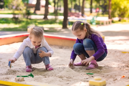 Happy little girls playing in a sendbox on the playgroundの写真素材