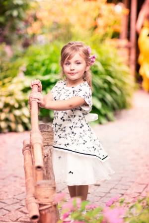 Charming little girl in a beautiful dress in a park outdoorの写真素材