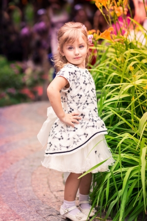 Charming little girl in a beautiful dress in a park outdoorの写真素材