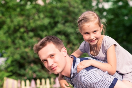 Happy smiling young father and daughter playing in the parkの写真素材