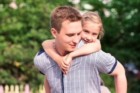 Happy smiling young father and daughter playing in the parkの写真素材