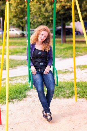 Beautiful little girl on a swings outdoor in the playground at summertimeの写真素材