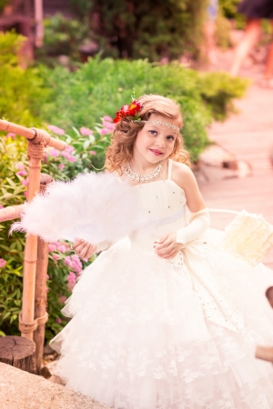 Charming little girl in a beautiful dress in a park outdoorの写真素材